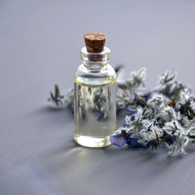 Illustration of a bottle labeled 'Lavender Oil' against a background of lavender flowers, symbolizing the use of lavender oil as part of the Kerassentials components
